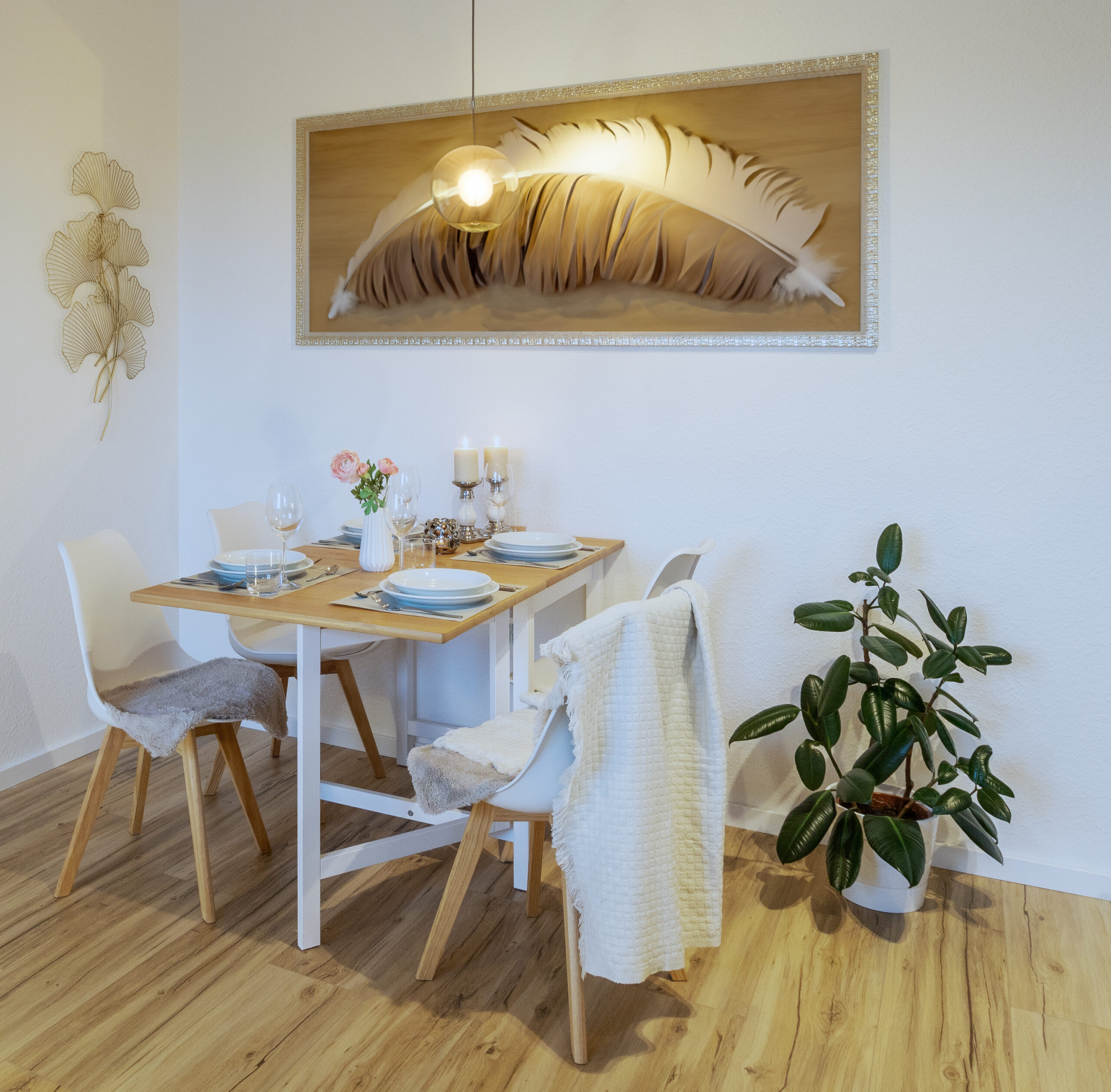 nach dem Staging: gedeckter Esstisch, Bild mit Feder, Wanddeko in Form eines Gingkoblatts