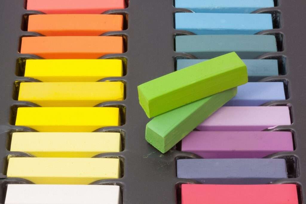 Kreide bunte Kreis in Regenbogenfarben in einer Schachtel sortiert, zwei Grüntöne liegen oben auf