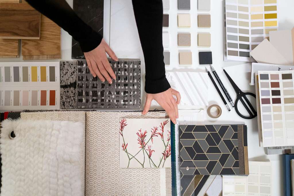 Mood Board ein Tisch mit Farbkarten, Stoff- und Materialproben sowie zwei Händen, die die Objekte arrangieren